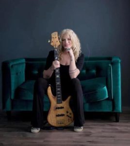 Blonde girl sitting on a green sofa with an electric guitar
