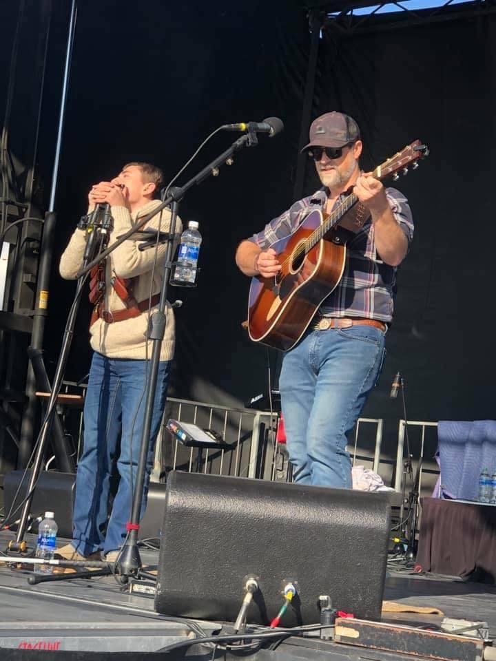two men on stage in blue jeans performing live