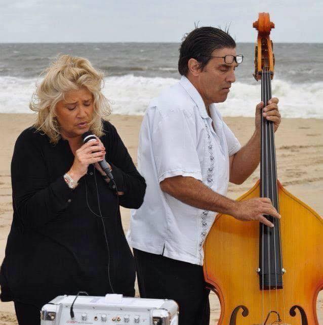 man and woman performing live music on the beach
