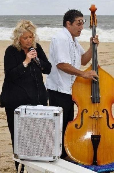 man and woman on the beach singing and playing music